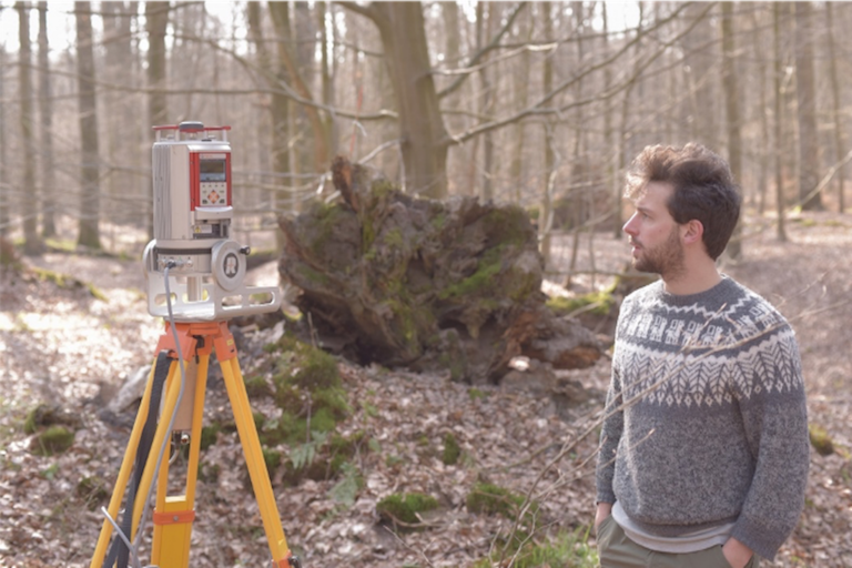 PhD student Miro DeMol standing next to a terrestial laser scanner
